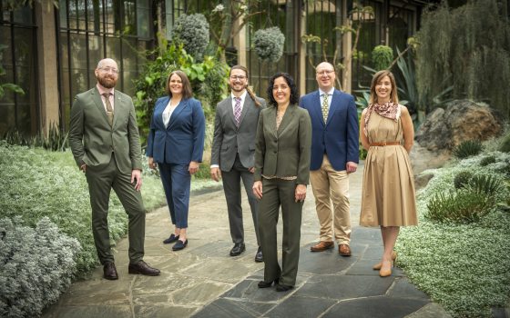 group of six people standing and facing the camera among a desert garden